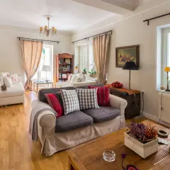 Przytulny salon w stylu angielskim, z wygodnymi sofami, drewnianą podłogą i ciepłymi zasłonami.