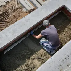 Budowlaniec wyrównuje podsypkę pod fundament. Solidny fundament to podstawa każdej budowy.