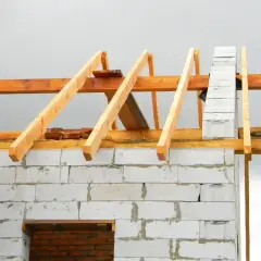 Budowa dachu dwuspadowego 100m2. Widoczna konstrukcja więźby dachowej z drewna na ścianach z bloczków.