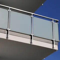 Nowoczesne mocowanie balustrady od czoła z matowego szkła i stali nierdzewnej, z widocznym niebieskim niebem w tle.
