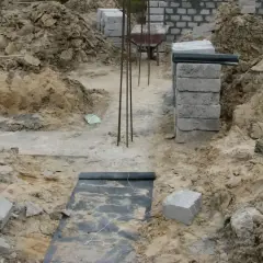 Wykonano wykopy pod fundamenty. Widać zbrojenie, betonowe bloczki i ziemię.