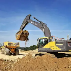 Koparka Volvo zasypuje wykop, przygotowując teren pod ułożenie rur. Cennik usług bez materiału.