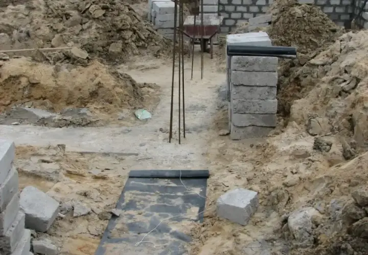 Wykonano wykopy pod fundamenty. Widać zbrojenie, betonowe bloczki i ziemię.