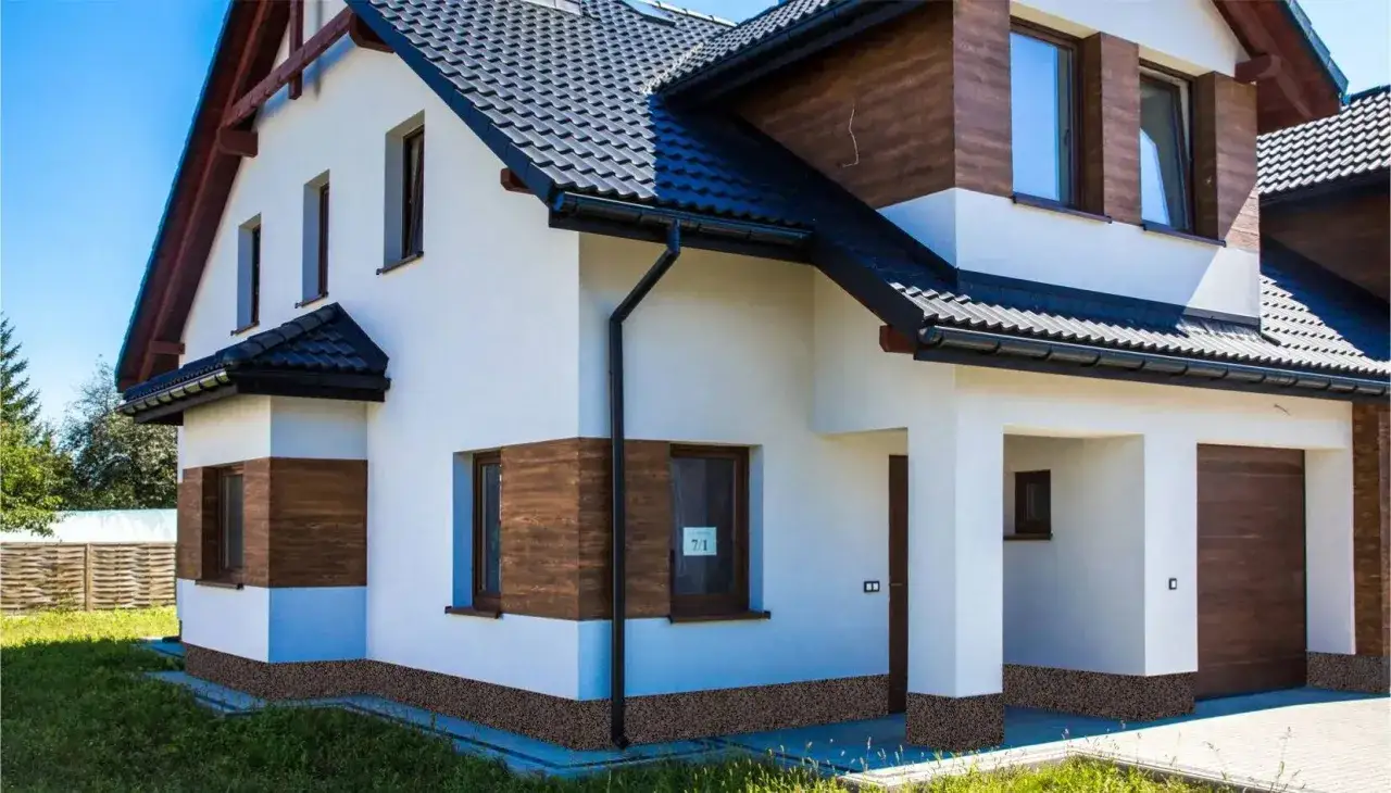 Nowoczesny dom z białym tynkiem i drewnianymi elementami. Tynk mozaikowy wydajność 25 kg na ok. 3-4 m².